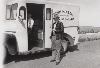 Milton Linscott in the milk truck driver's seat, with employer Hugh Kelley standing.